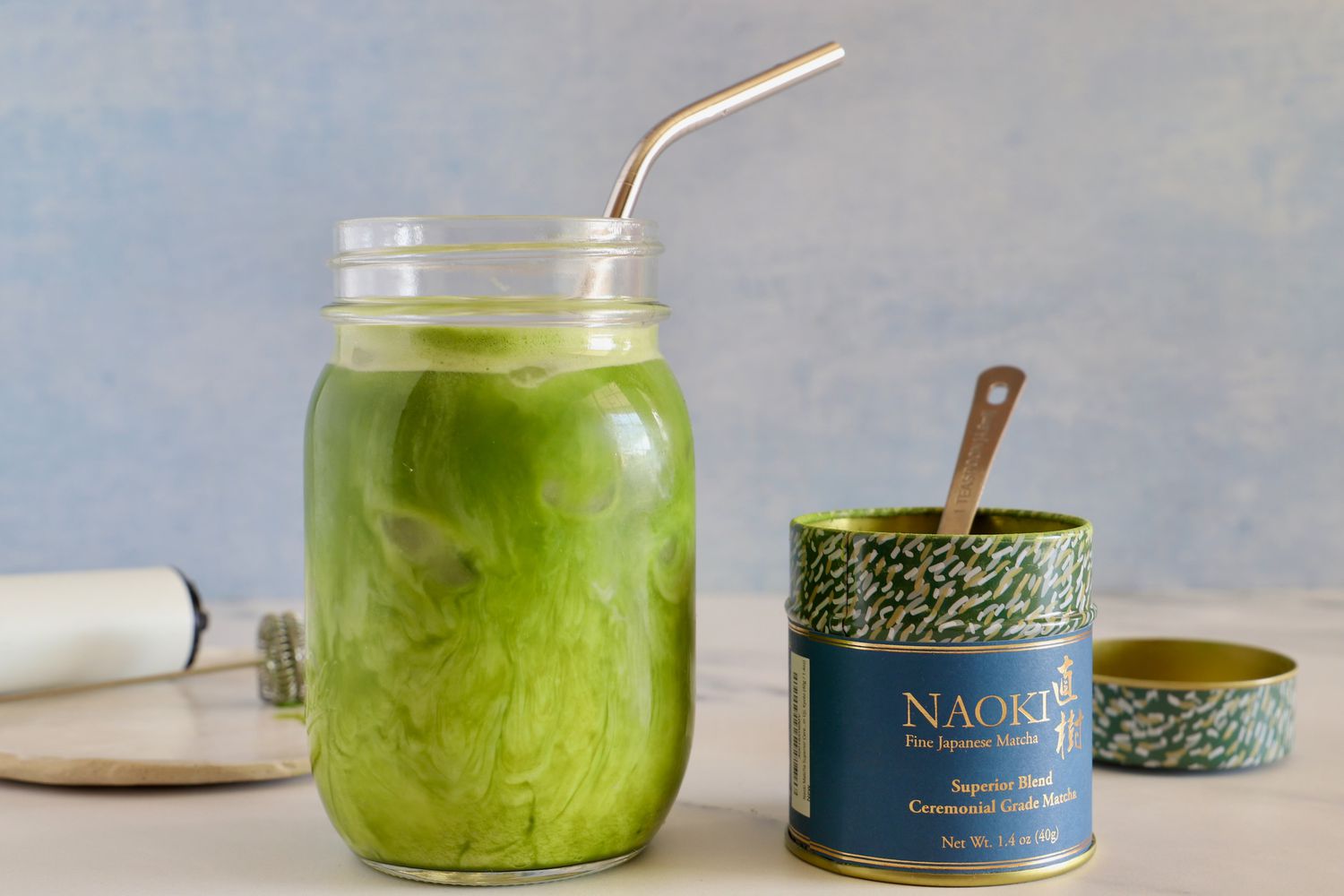A glass of Naoki Matcha Superior Ceremonial Blend next to the container