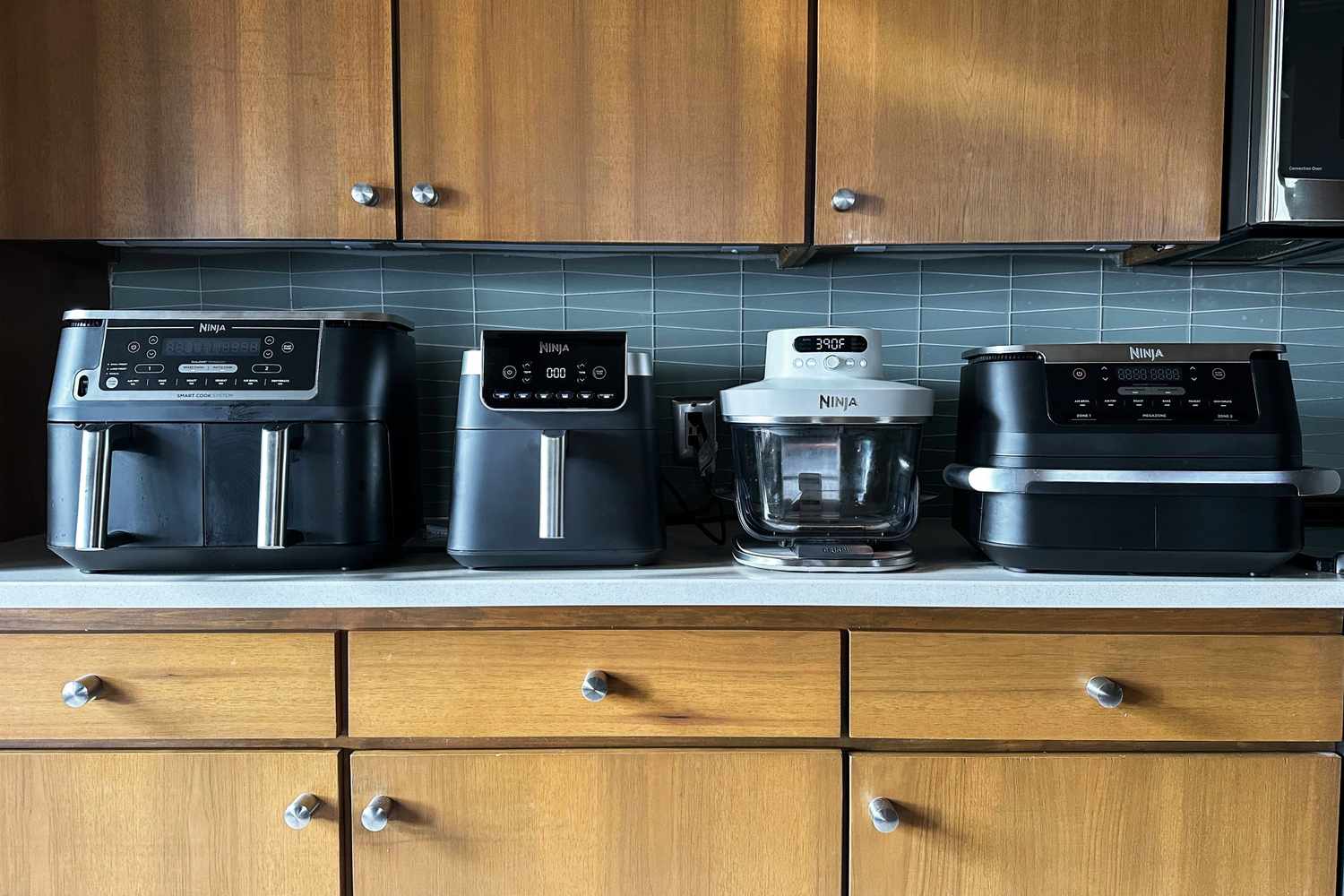 Four kitchen air fryers displayed on a countertop arranged in a row showcasing various models and designs