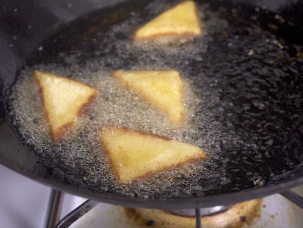 A wok holding shrimp toast frying in hot oil.