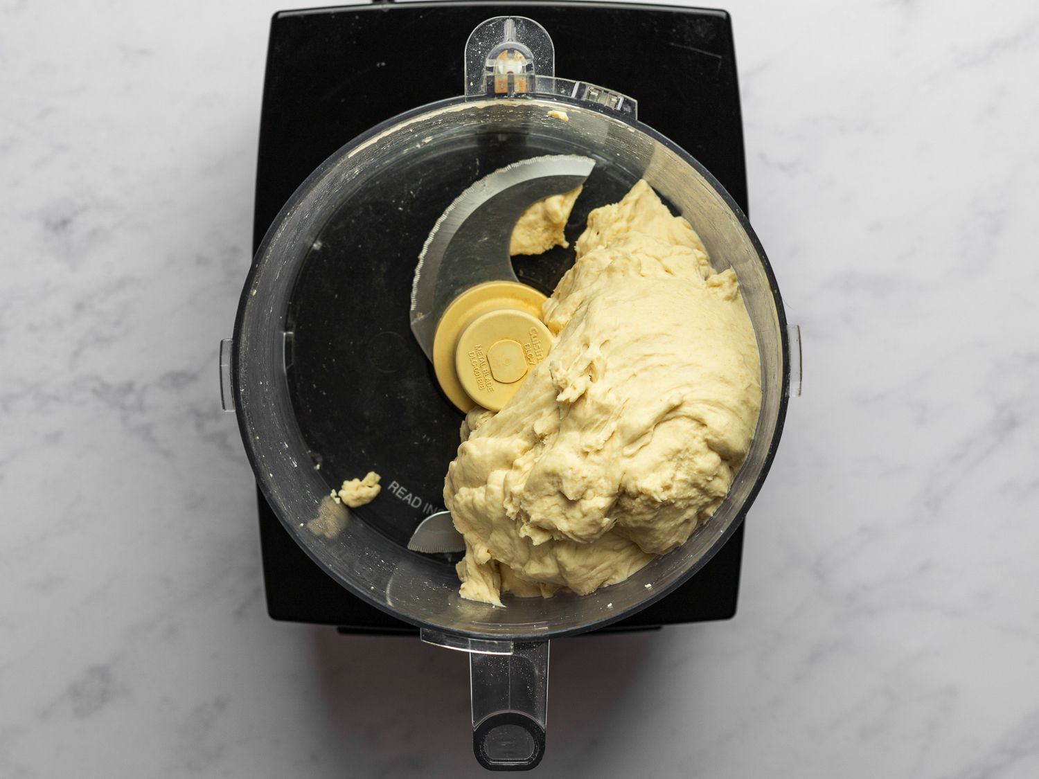 Dough formed inside food processor, with dough ball riding on top of the blade.