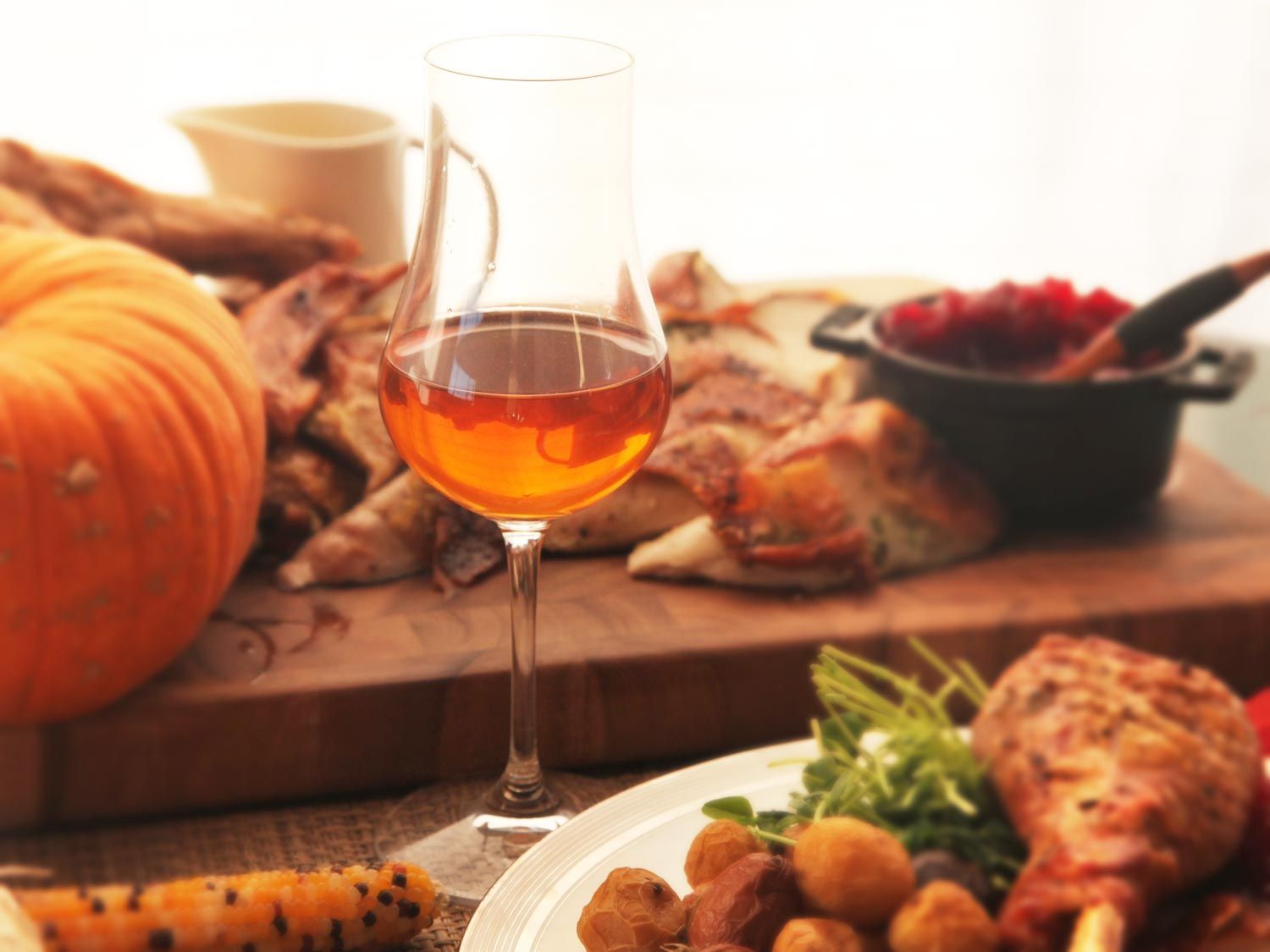 A glass of wine surrounded by a Thanksgiving spread.