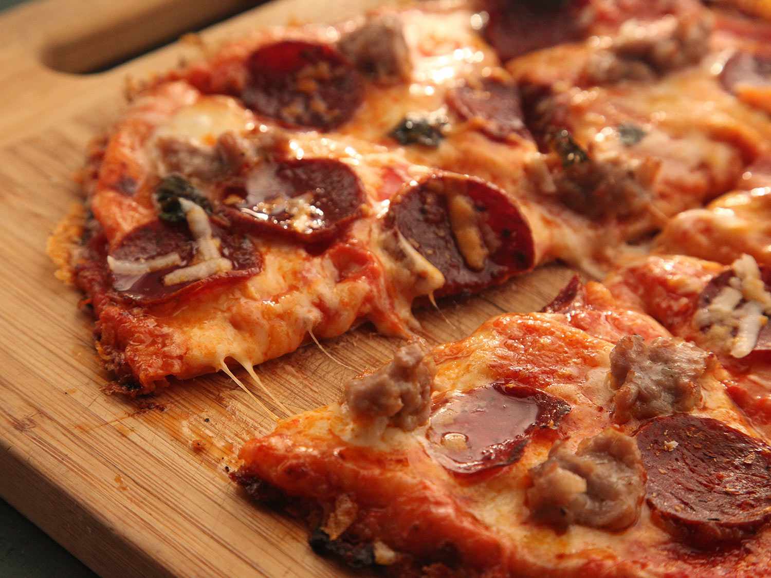 Side view of a detached wedge of quesadilla pizza with pepperoni and sausage.