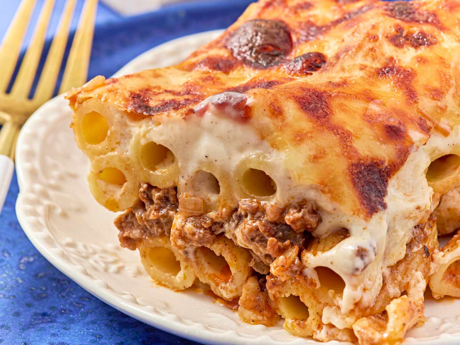 A slice of baked pasta with visible layers of rigatoni meat filling cheese and bchamel sauce on a plate