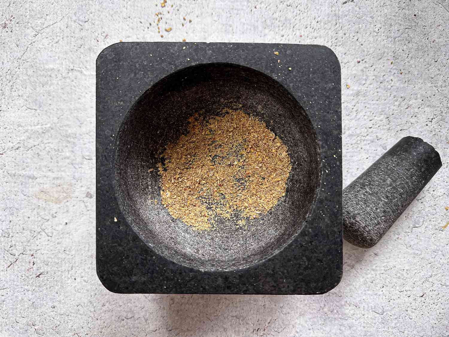 Mortar and pestle with peppercorns and coriander sees ground into a coarse powder 