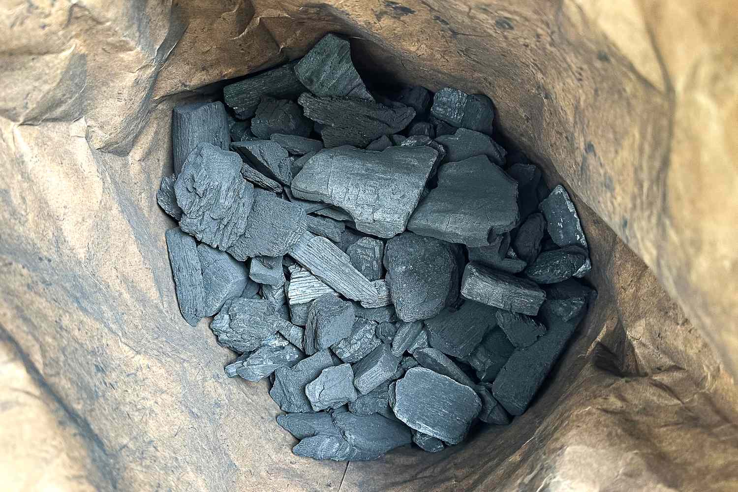 Several pieces of Royal Oak All Natural Hardwood Lump Charcoal inside a paper bag