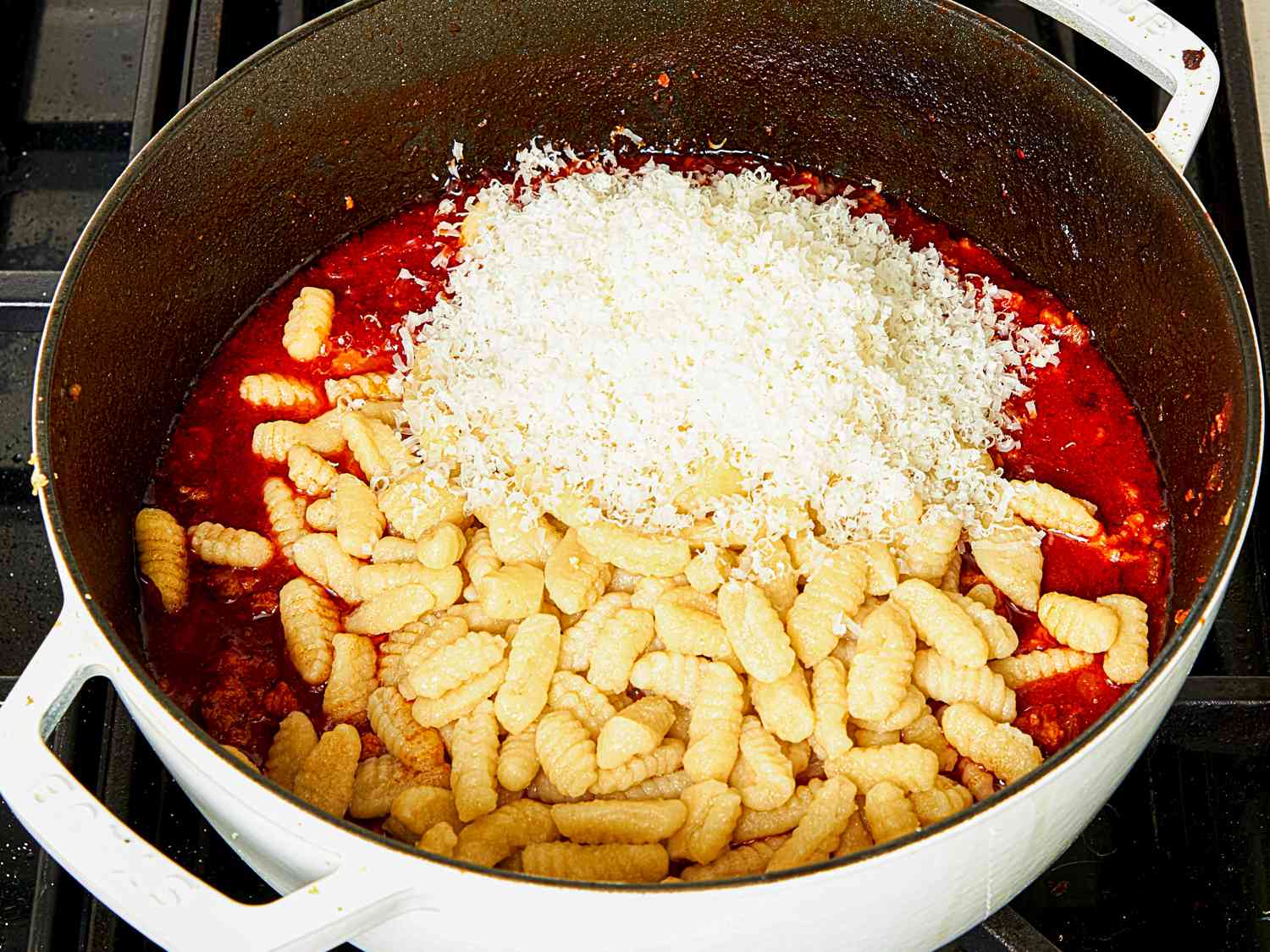 Overhead view of gnocchi with cheese added to the sauce