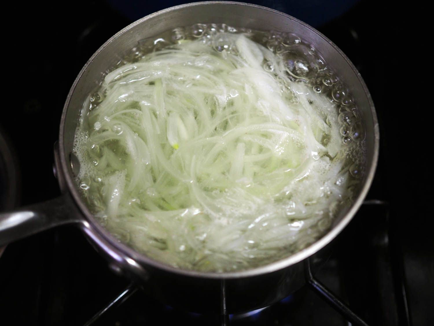 Sliced onions being blanched in salt water to test one method of soubise preparation.