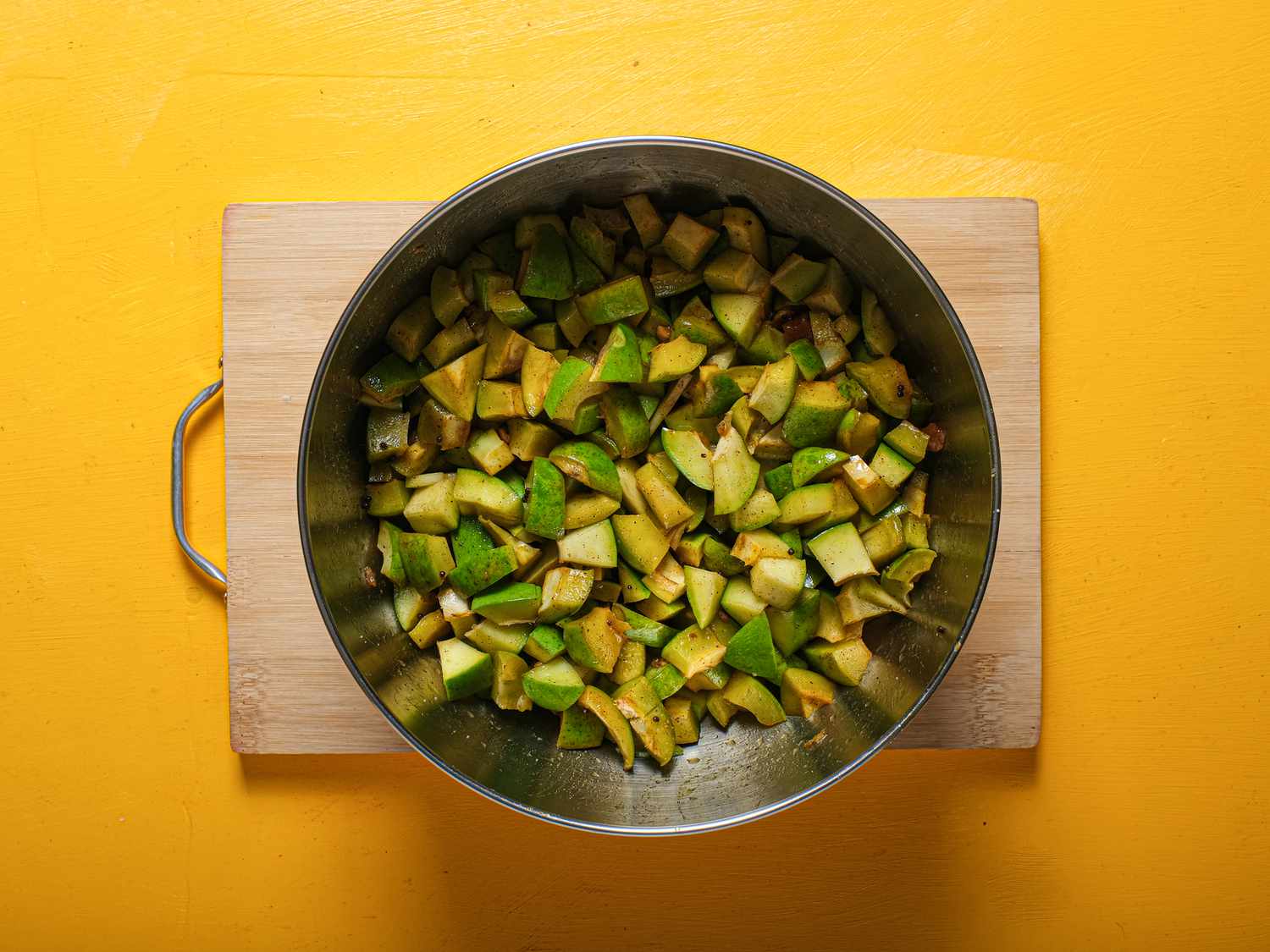 mango pickle after macerating in metal bowl, on wooden board 