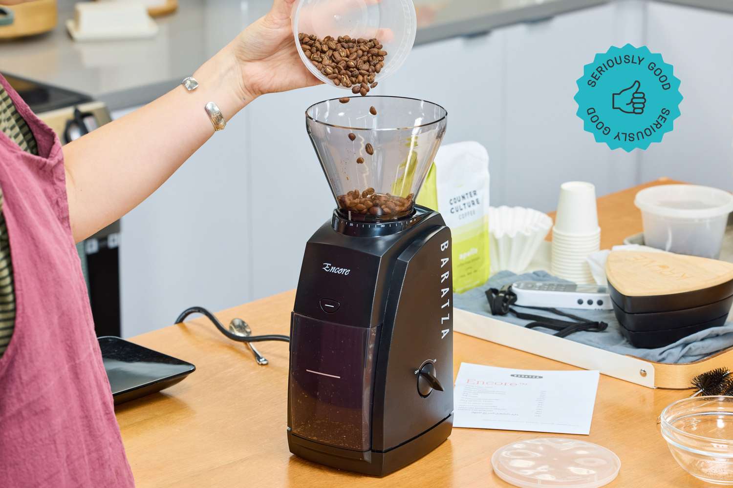 A person pours coffee beans into the Baratza Encore coffee grinder