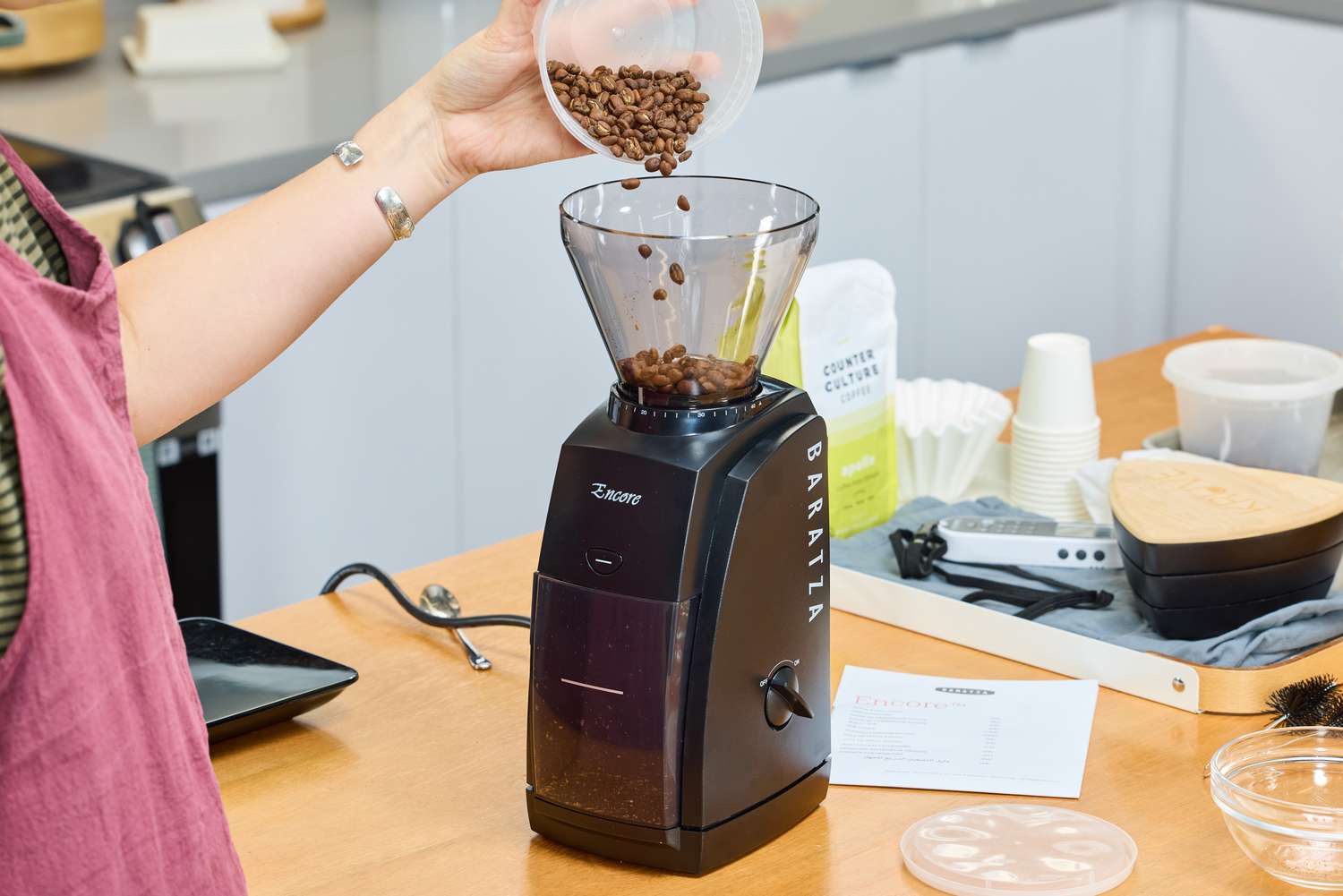 A person pours coffee beans into the Baratza Encore Conical Burr Coffee Grinder