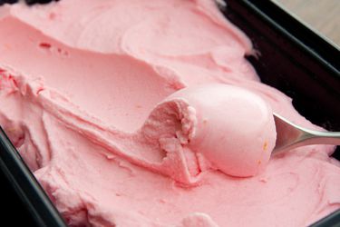 Closeup of blood orange sherbet in a shallow storage container.