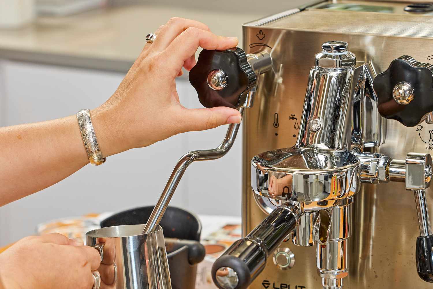 A hand holding a nob while steaming milk with the Lelit MaraX Espresso Machine PL62X-120