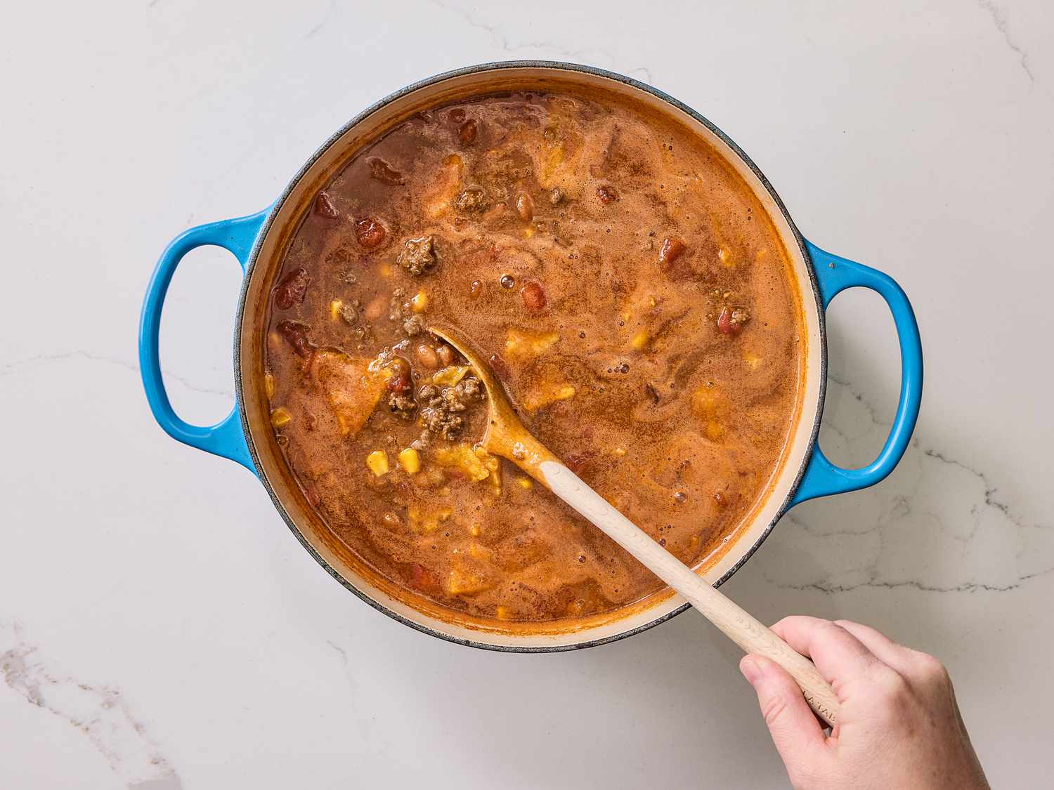 Mixing dutch oven taco soup with a wooden spoon 