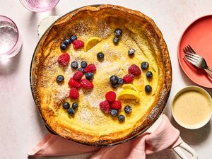 A baked Dutch baby pancake with berries and lemon slices on top