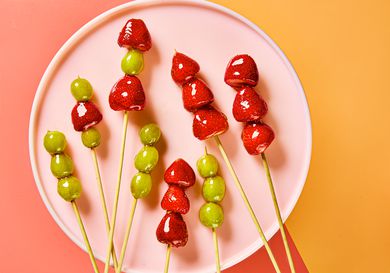 Tanghulu sticks on a pink circular plate, with a pink and orange background
