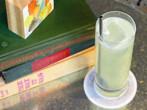 A Phil Collins cocktail in a tall glass next to a stack of books.