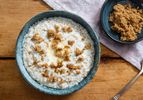 Overhead view of a blue ceramic bowl filled with creamy Irish-style oatmeal with brown sugar. A small bowl of brown sugar is nearby.
