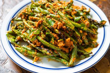 A plate of dry-fried green beans with romesco sauce.