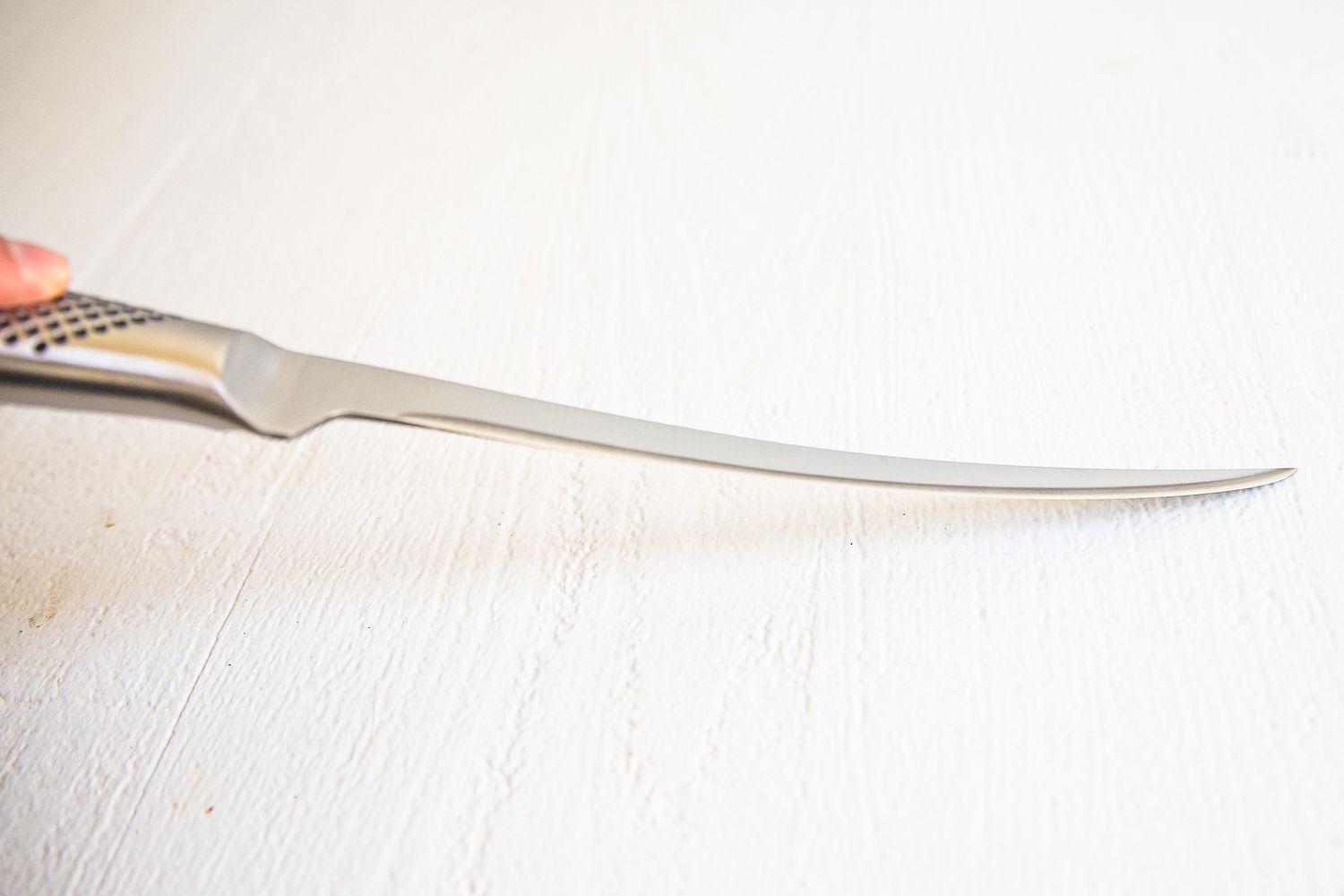 A curved knife with a textured handle resting on a white surface