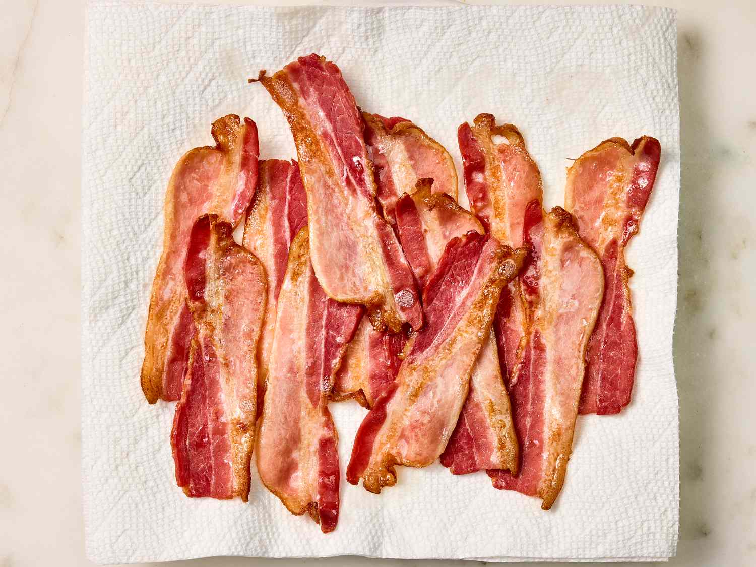 Cooked bacons draining on a paper towel lined plate 