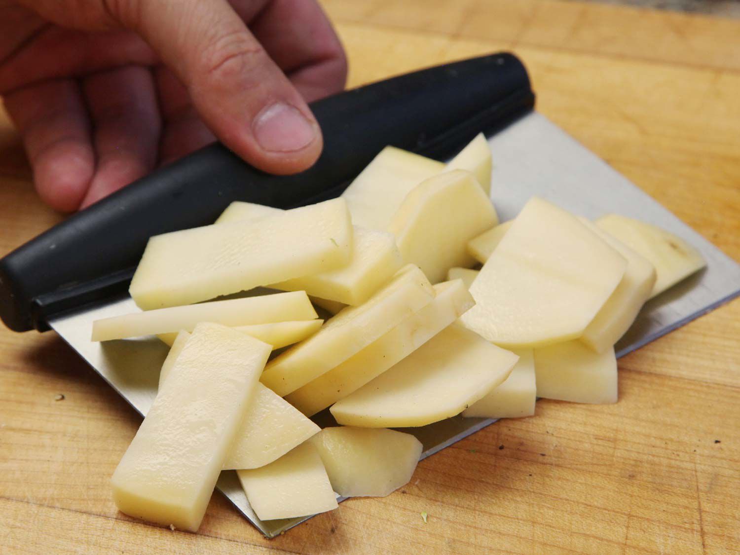 Scooping potato slices with a benchscraper. 