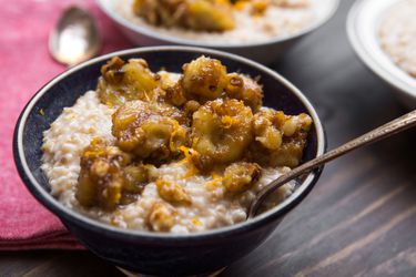 Bananas Foster oatmeal, served in a dark ceramic bowl.