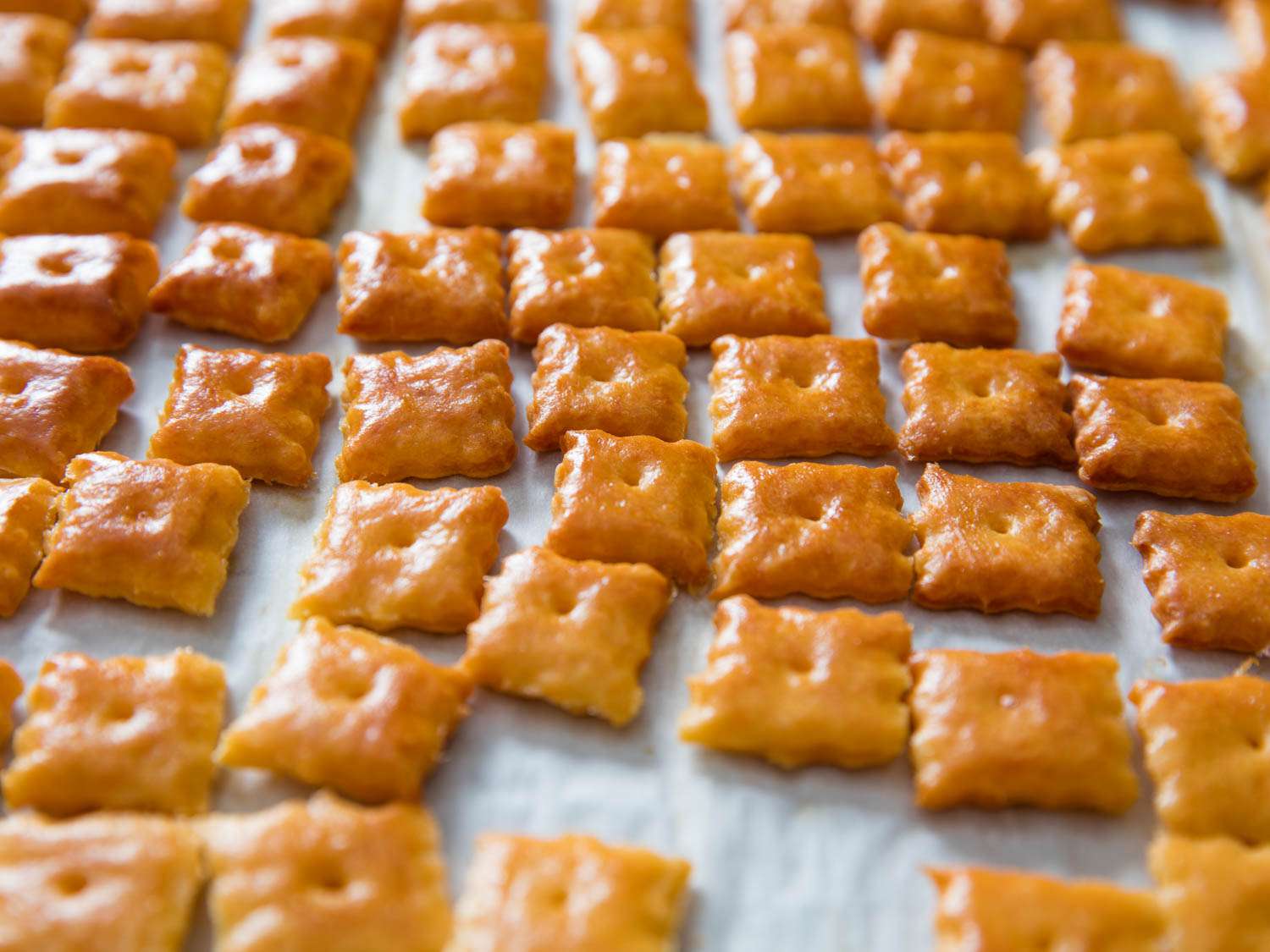 Close-up of cheez-its arranged on parchment, fresh from the oven.