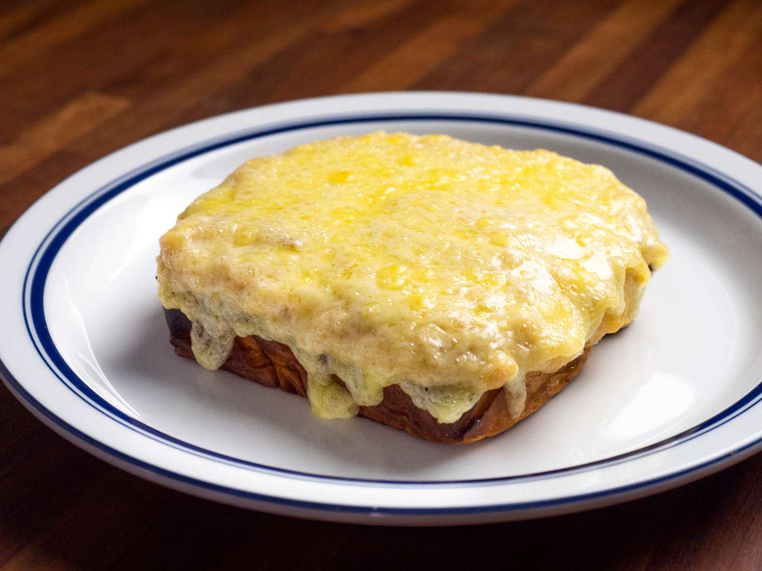 An open-faced tuna melt with white cheddar thoroughly melted and dripping down the sides