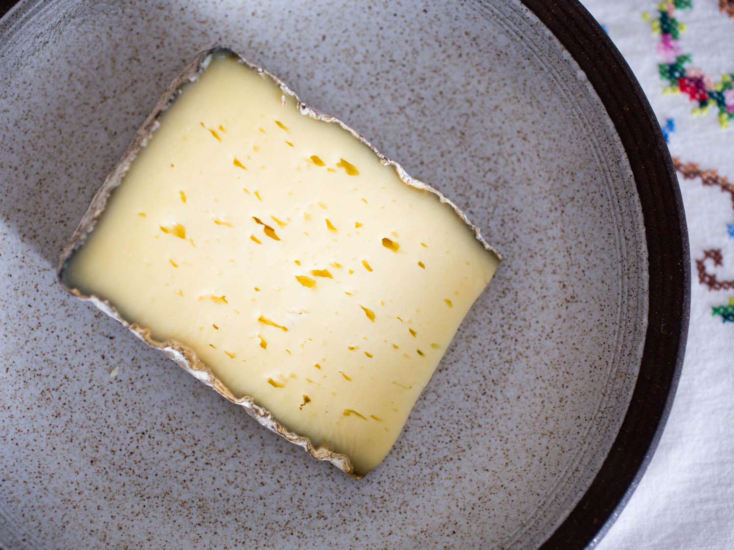 A wedge of Weinkase Lagrein cheese on a speckled gray plate. 