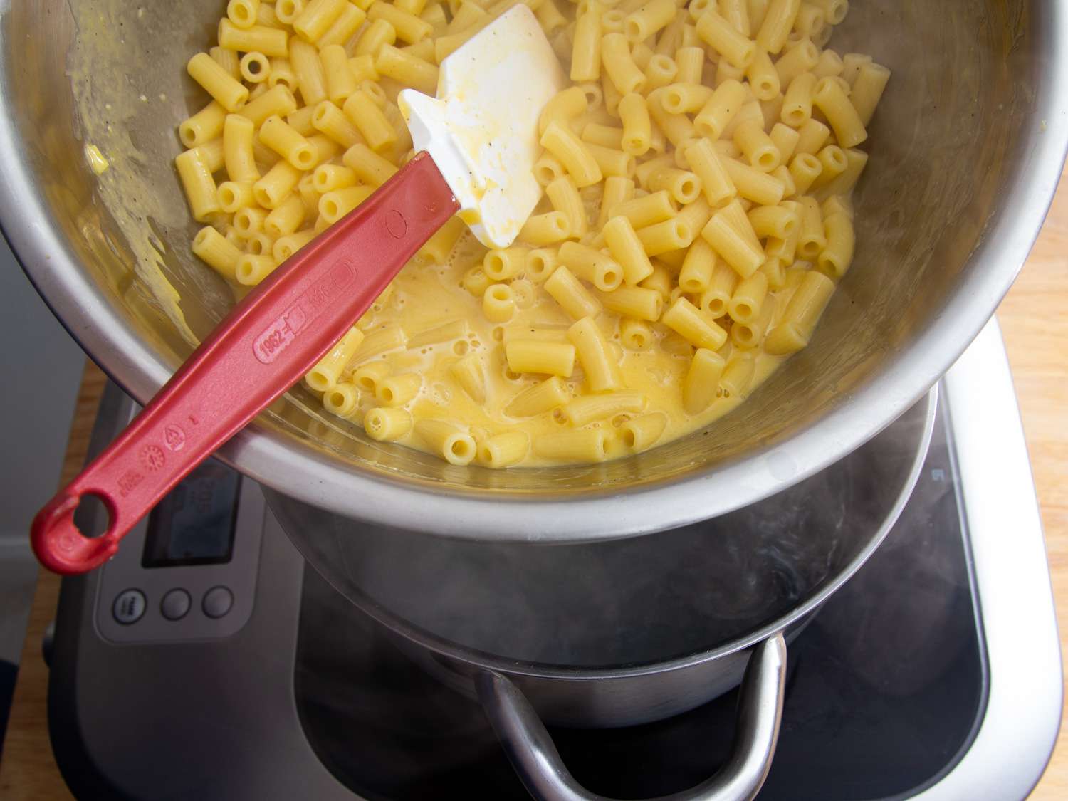 Stirring pasta with a spatula until sauce is creamy and coats everything.