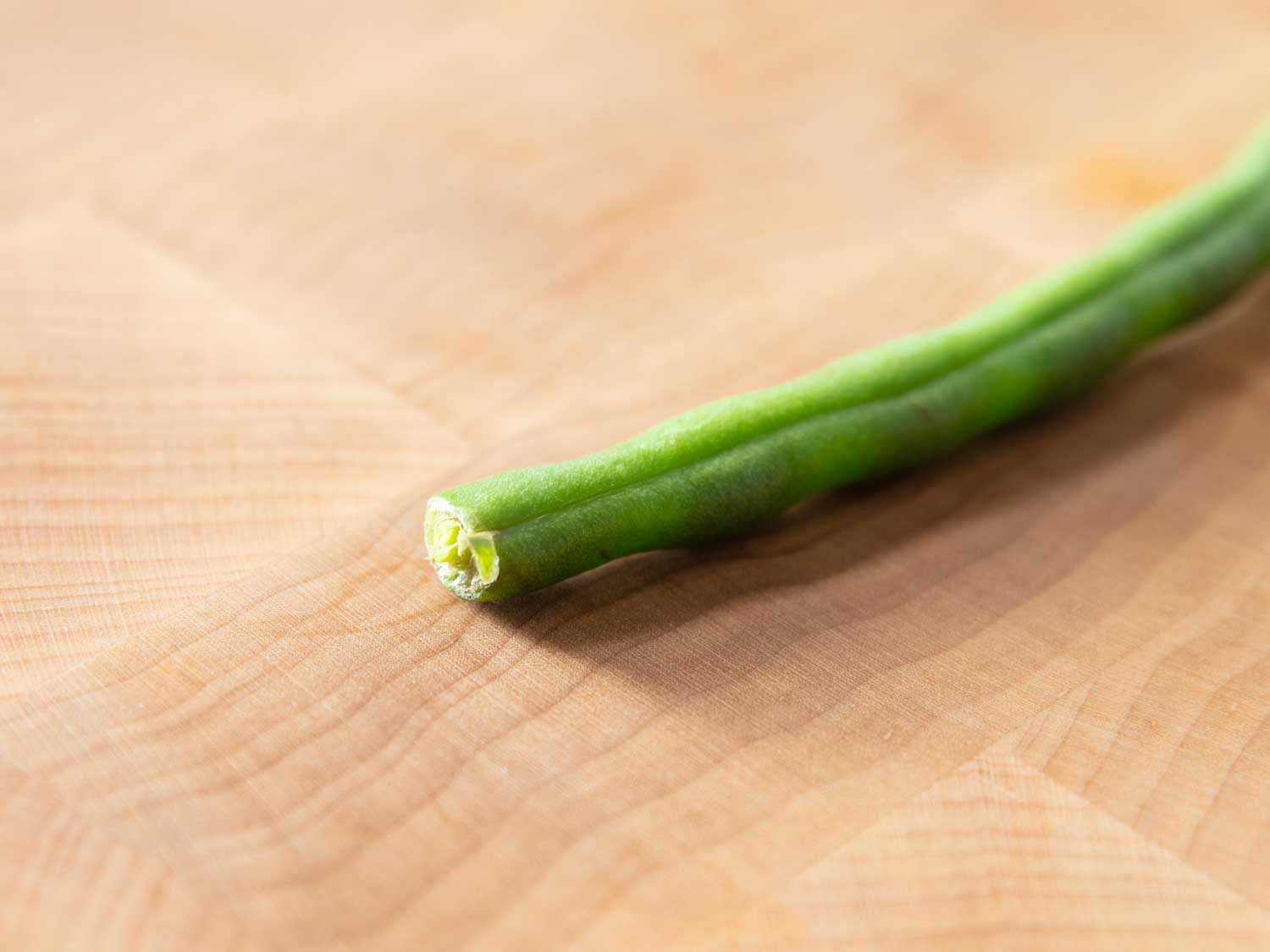 Closeup of the shriveled, dried out end of a green bean that was already trimmed before purchasing. This needs to be trimmed again.