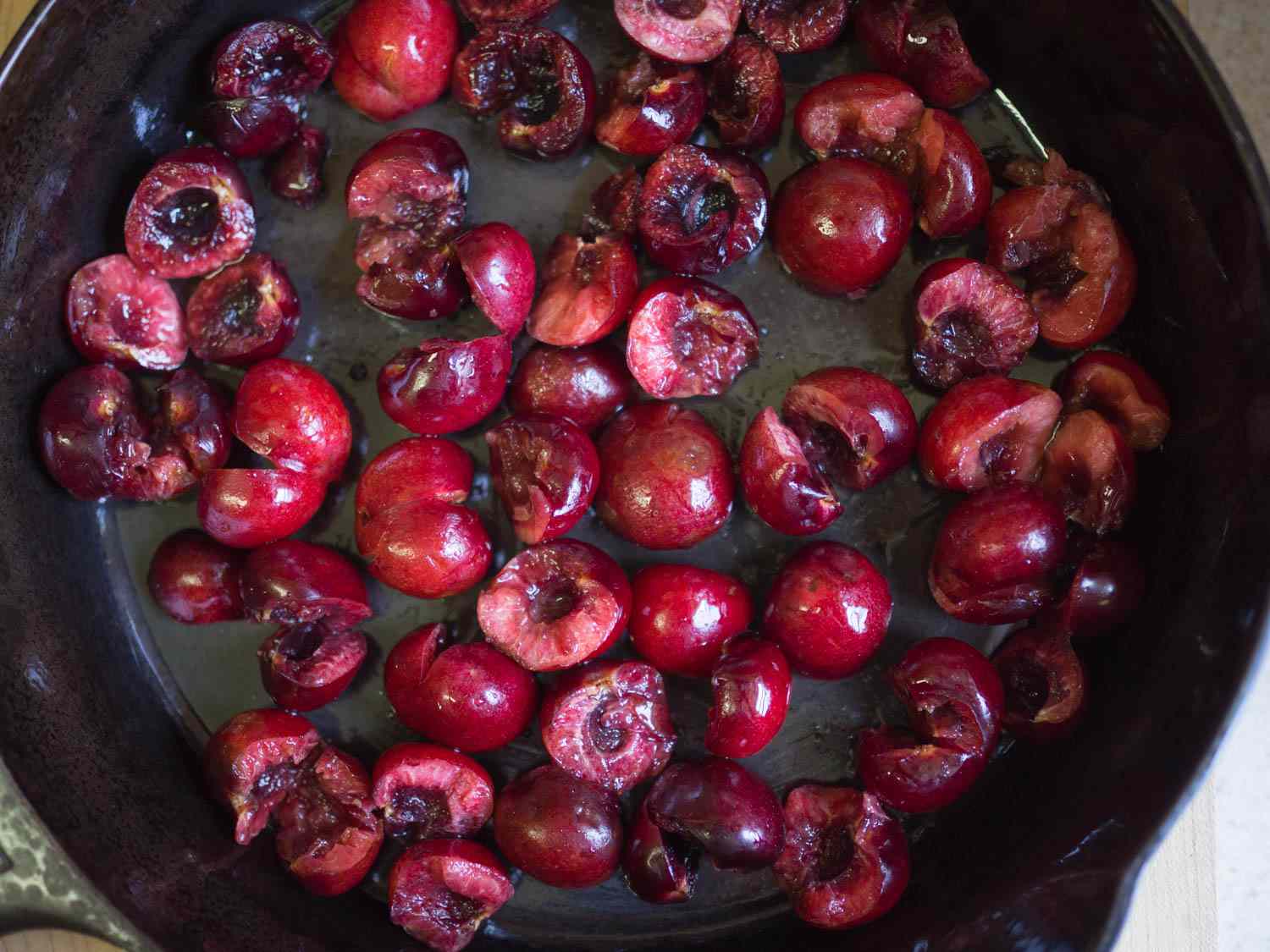 Pitted cherries scattered in a cast iron skillet.