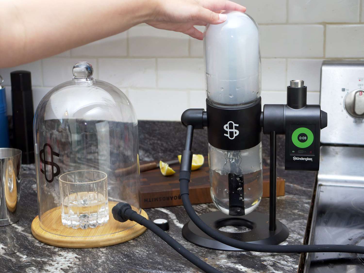 a hand pushing down the top vial in the stundenglass cocktail smoker