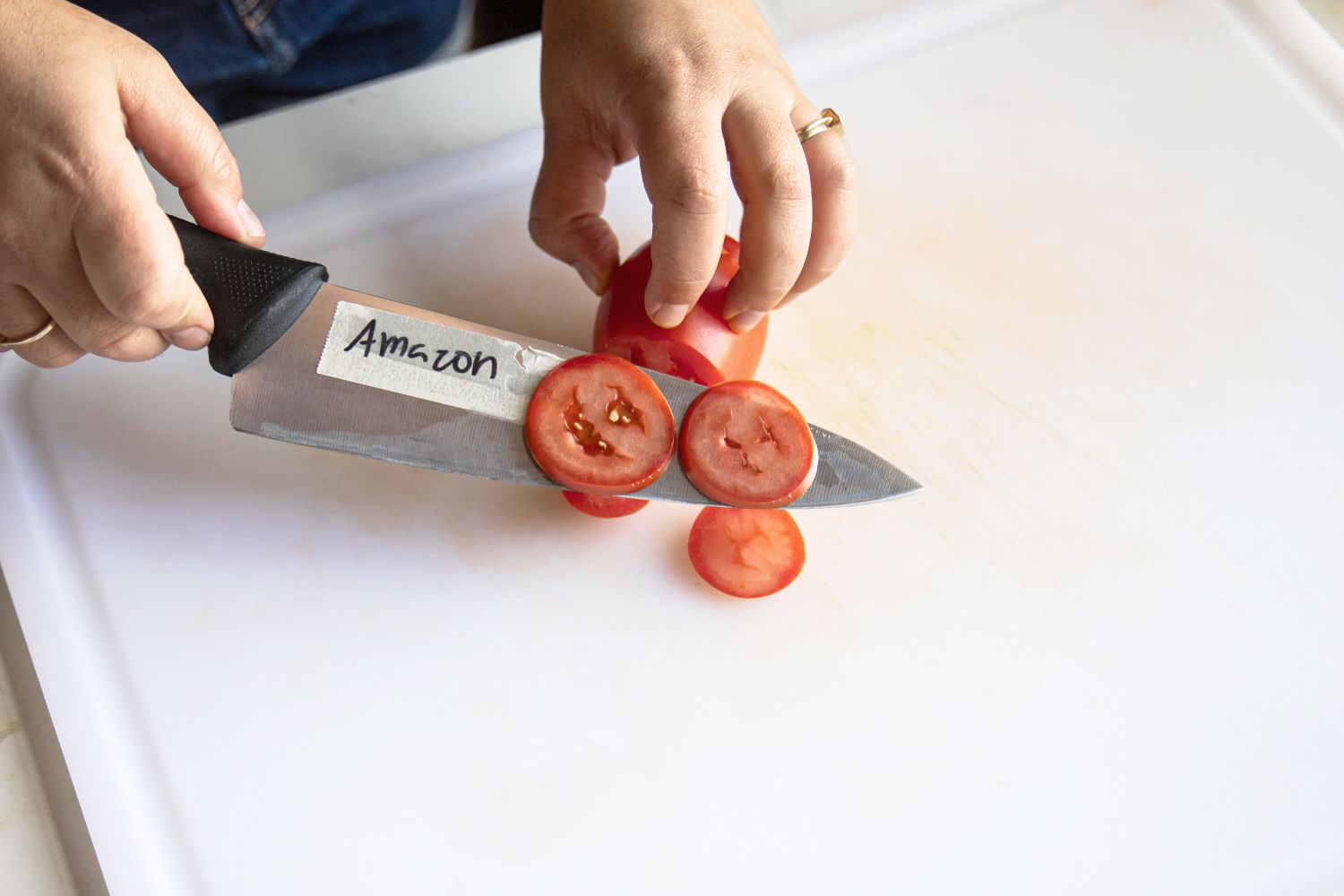 A person thinly slicing a tomato
