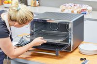 A person taking an empty rack out of the KitchenAid Dual Convection Countertop Oven with Air Fryer