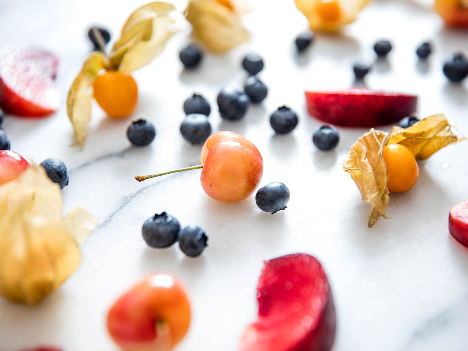 A white marble slab strewn with late-summer fruit for a homemade pie