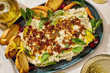 Platter of whipped ricotta dip garnished with herbs and served with toasted baguette slices