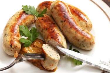 A plate of cooked weisswurst, garnished with parsley.