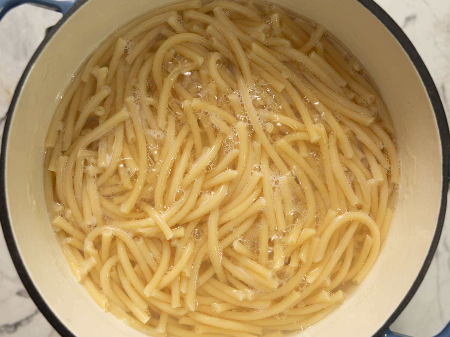 A pot filled with cooked pasta noodles in water on a stovetop