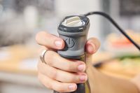 A person presses the power button on the Breville Control Grip Immersion Blender