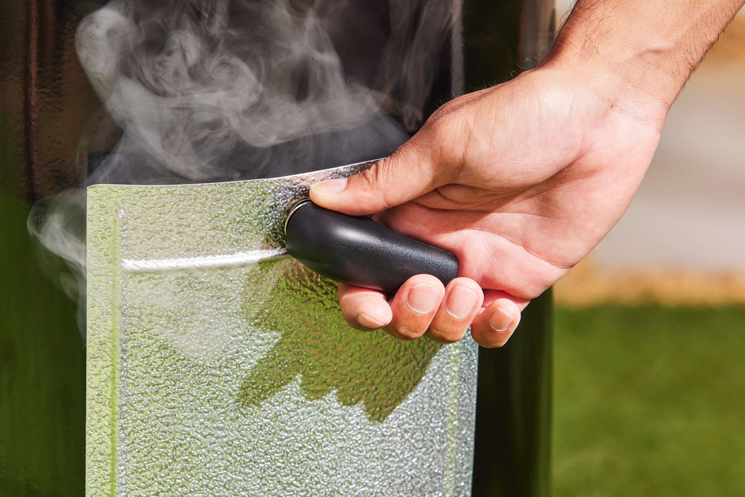 A person adjusts the Weber Smokey Mountain Cooker 18-Inch Charcoal Smoker (721001)