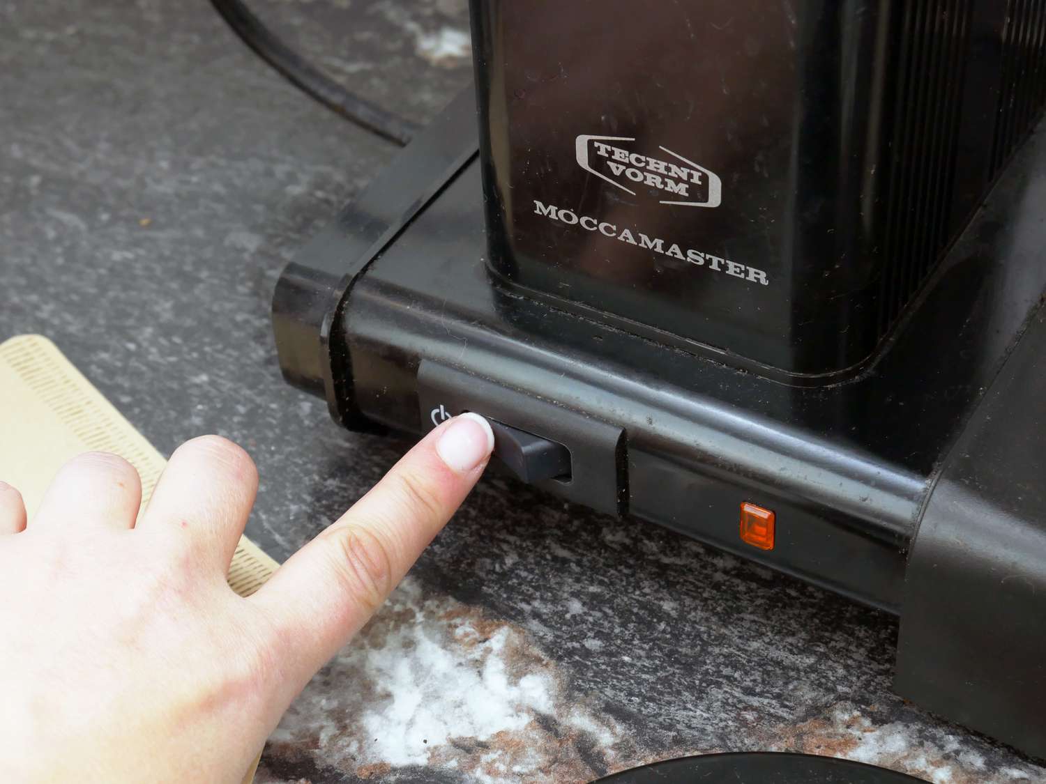 a person turning on the coffee maker. 