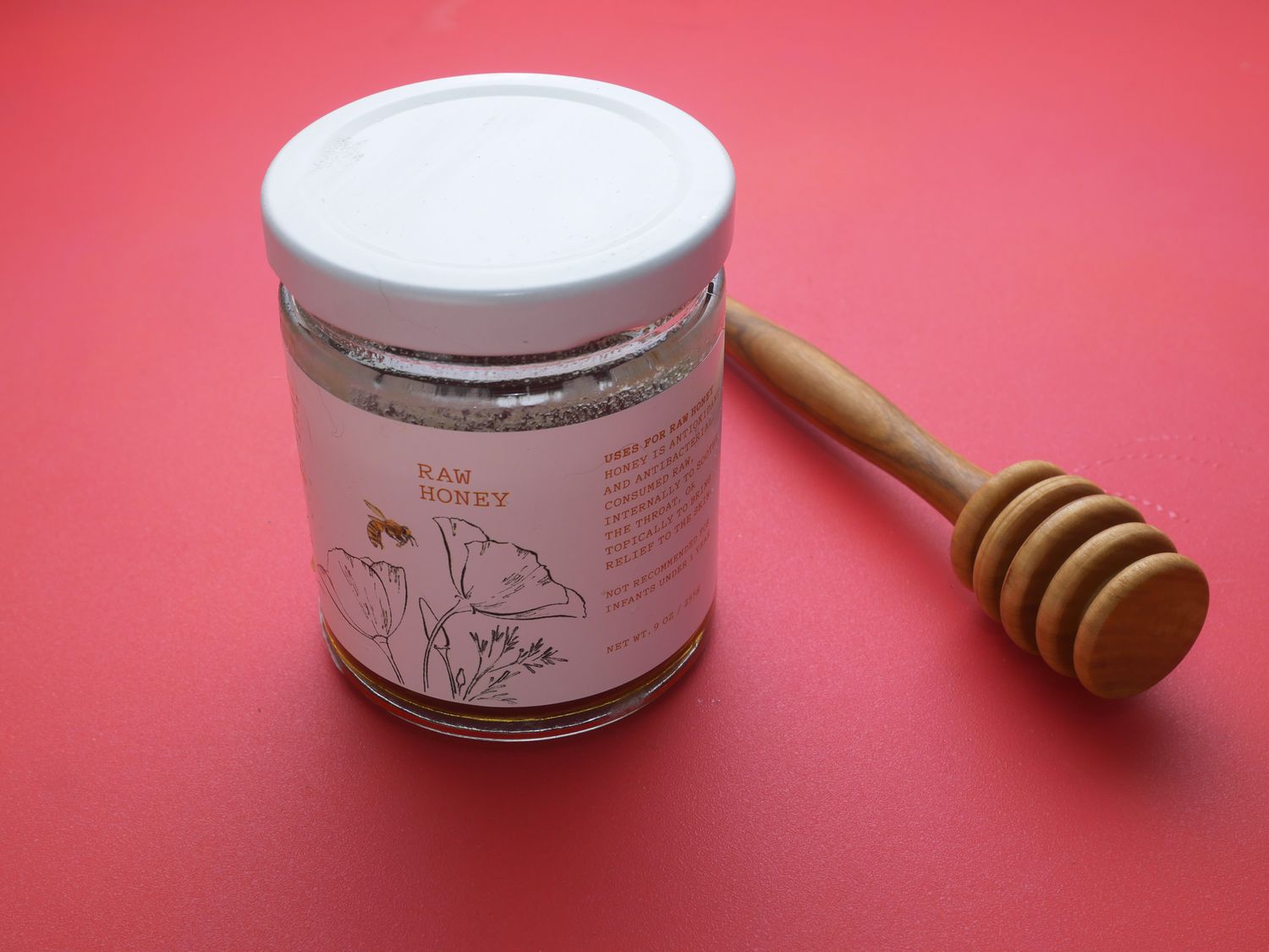 sonoma county honey on a red backdrop with honey dripper to side