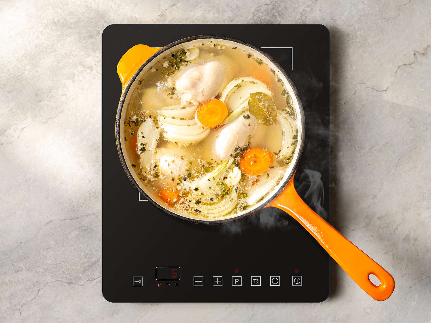 Chicken, carrots, onion and herbs poaching in a pot 