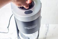 Hand pressing down on the lid of a Hawaiian Shaved Ice HomePro Shave Ice and Snow Cone Machine (S777) shaved ice machine