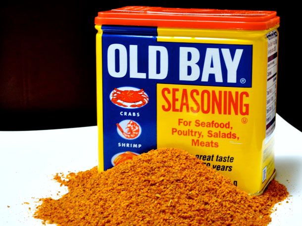 A tin of Old Bay seasoning with a pile of seasoning in front of it.
