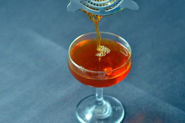 A Fanciulli cocktail being strained and poured into a coupe from a cocktail shaker.