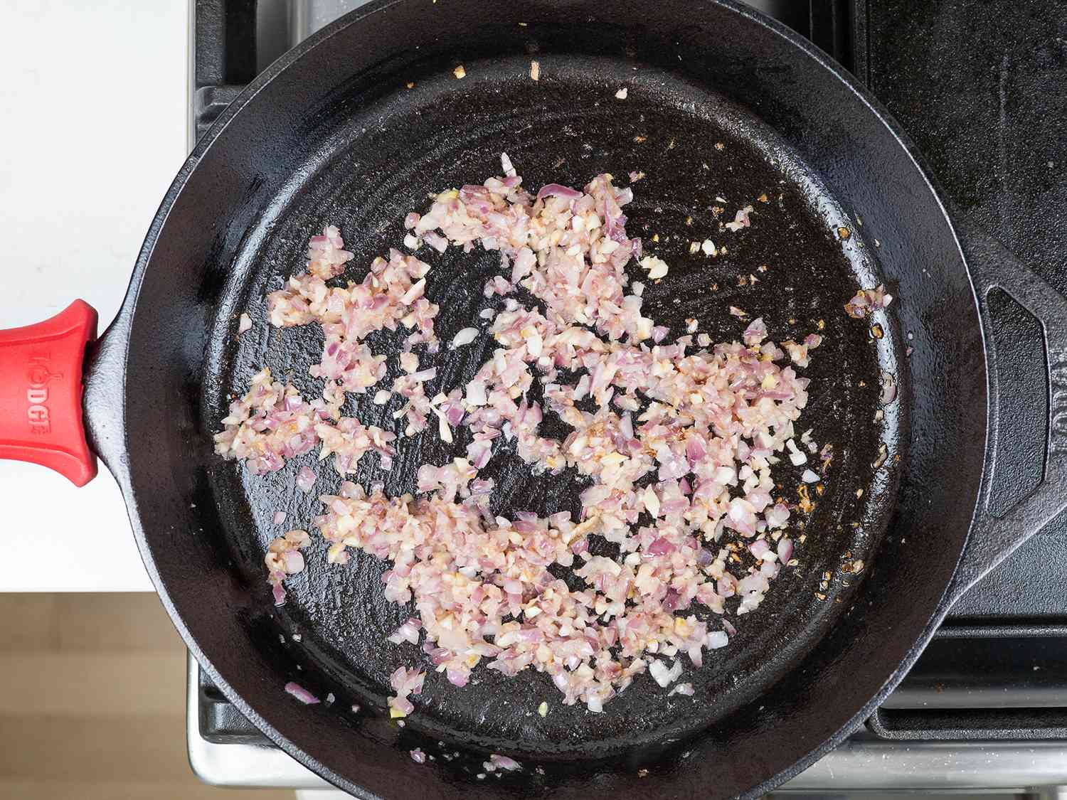 Onion and garlic being cooked in a cast iron pan.