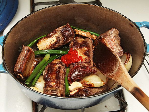 Scallions and a bright spoonful of gochujang are added to the pot.