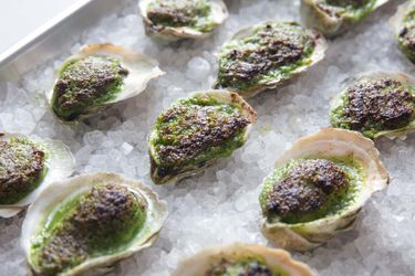 A baking sheet of Oysters Rockefeller resting on a layer of rock salt